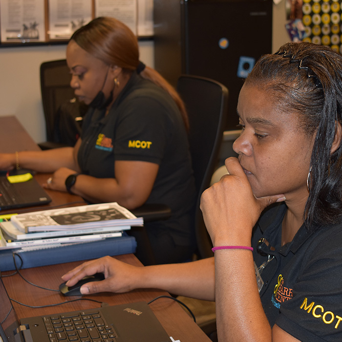 Two female African American members of the MCOT team working at their desks.