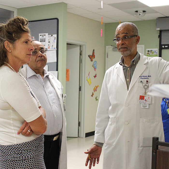 A woman is consulting with two male healthcare workers in a hospital environment.