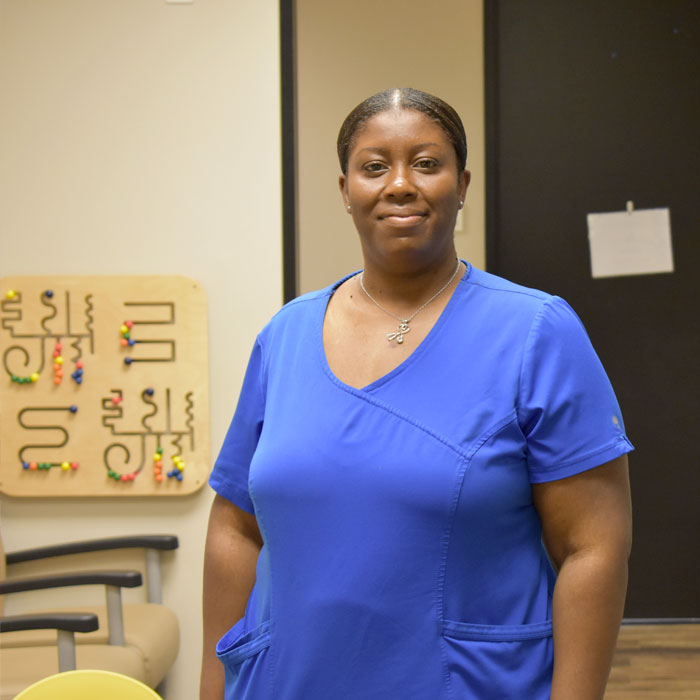 The Harris Center staff member standing for a portrait in their work setting with a children's learning toy in the background