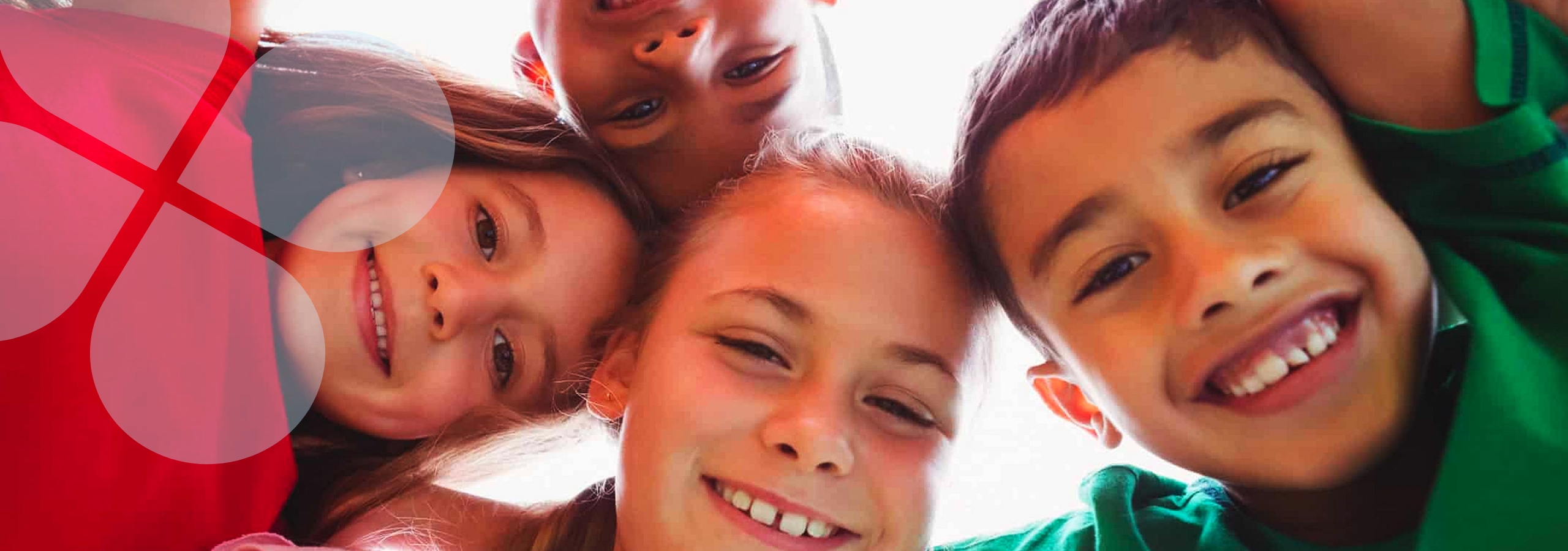 Children in a circle smiling down at the camera