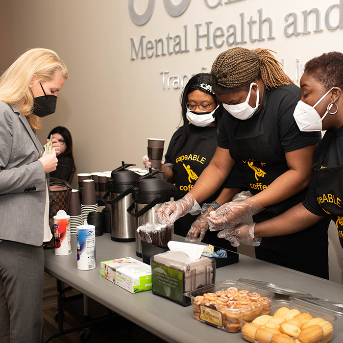 A woman is buying coffee from vendors at a charity event hosted by the Harris Center.