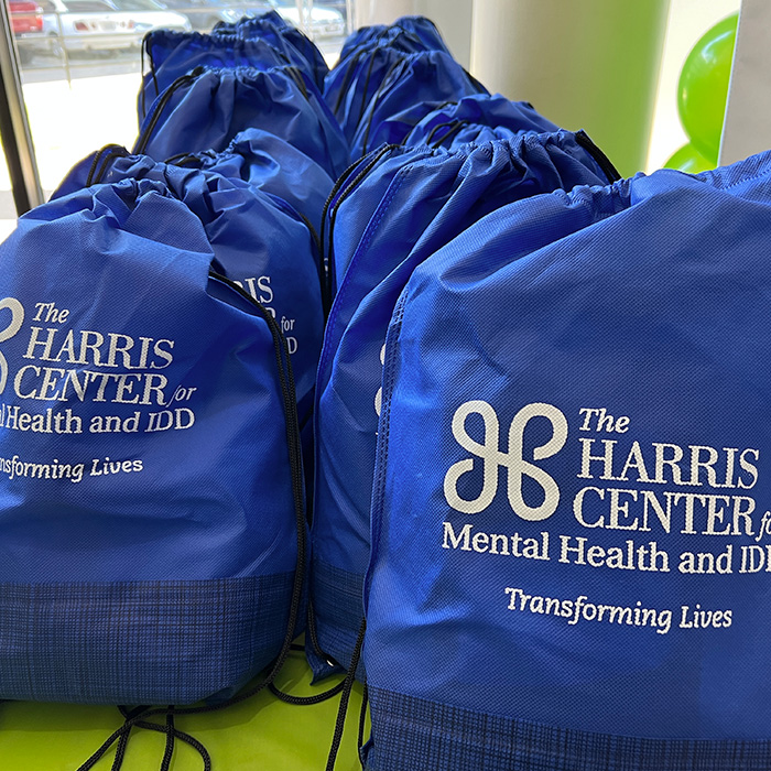 Several drawstring bags with the Harris Center logo printed on them.