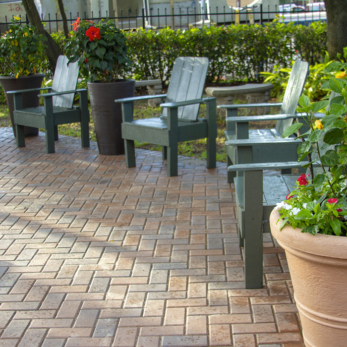 Exterior view of patio chairs and flowering plants on a patterned brick area