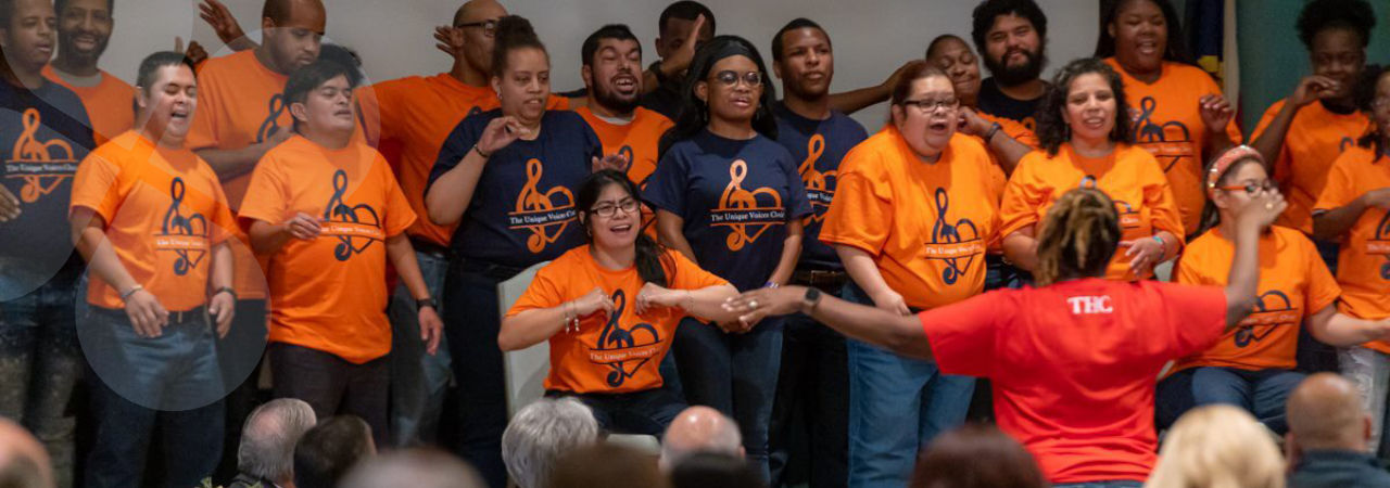 Choir members wearing matching t-shirts, performing for loved-ones and acquaintances