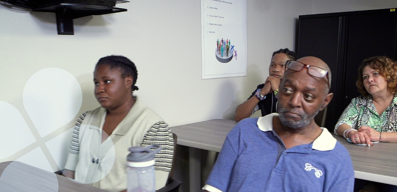 Four people at tables in a classroom setting at a Harris Center service provider facility