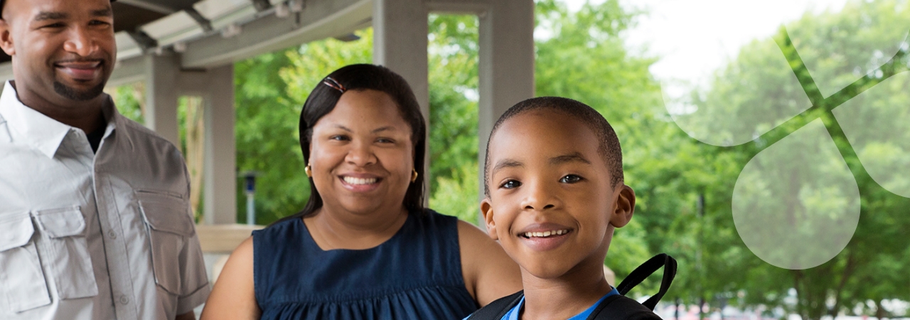 Smiling family outdoors with child in foreground