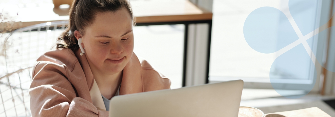 Young person sitting in a sunny café setting, working with a laptop