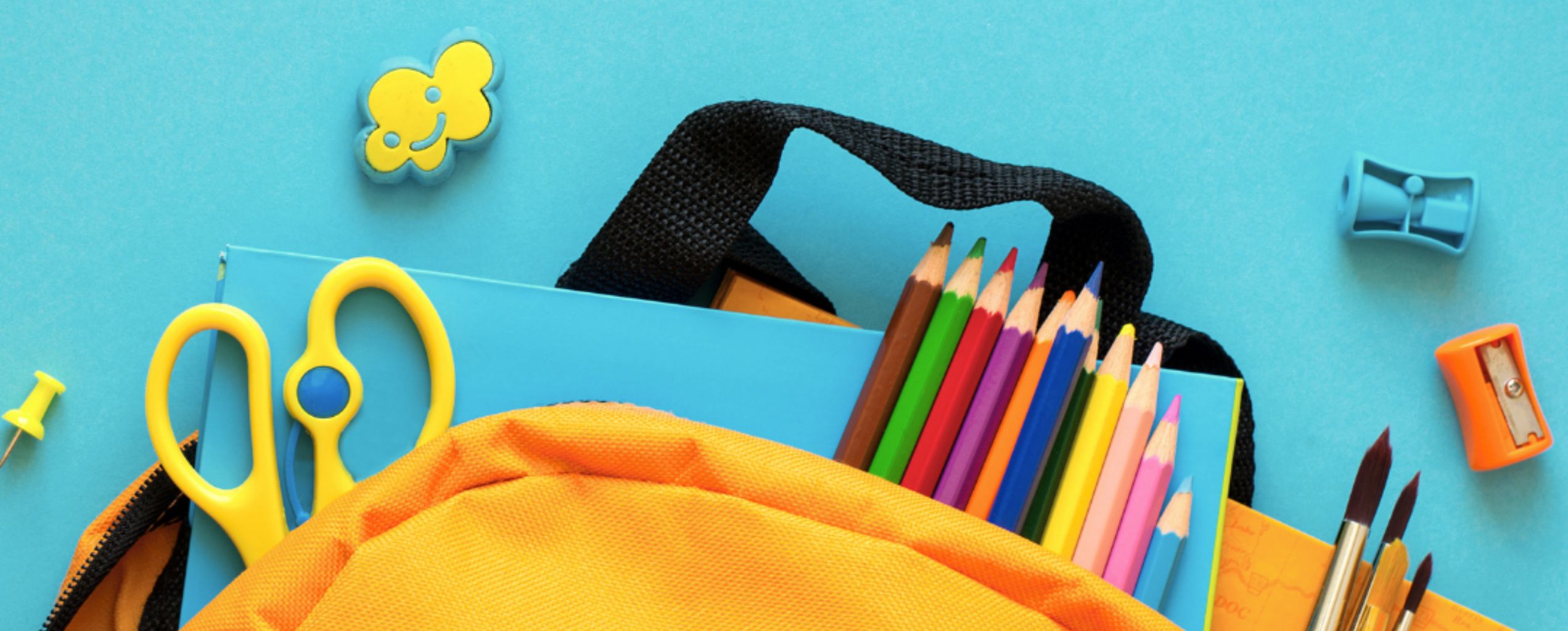 Back-to-school supplies including colored pencils, scissors, notebooks, paintbrushes, sharpeners, and a yellow backpack on a blue background.