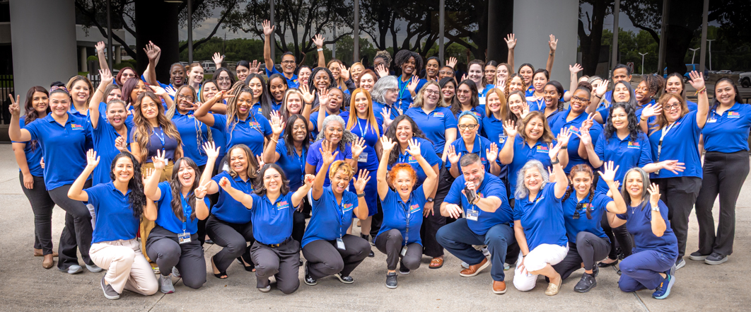 Large group of ECI team members making silly faces and wearing their blue uniforms.