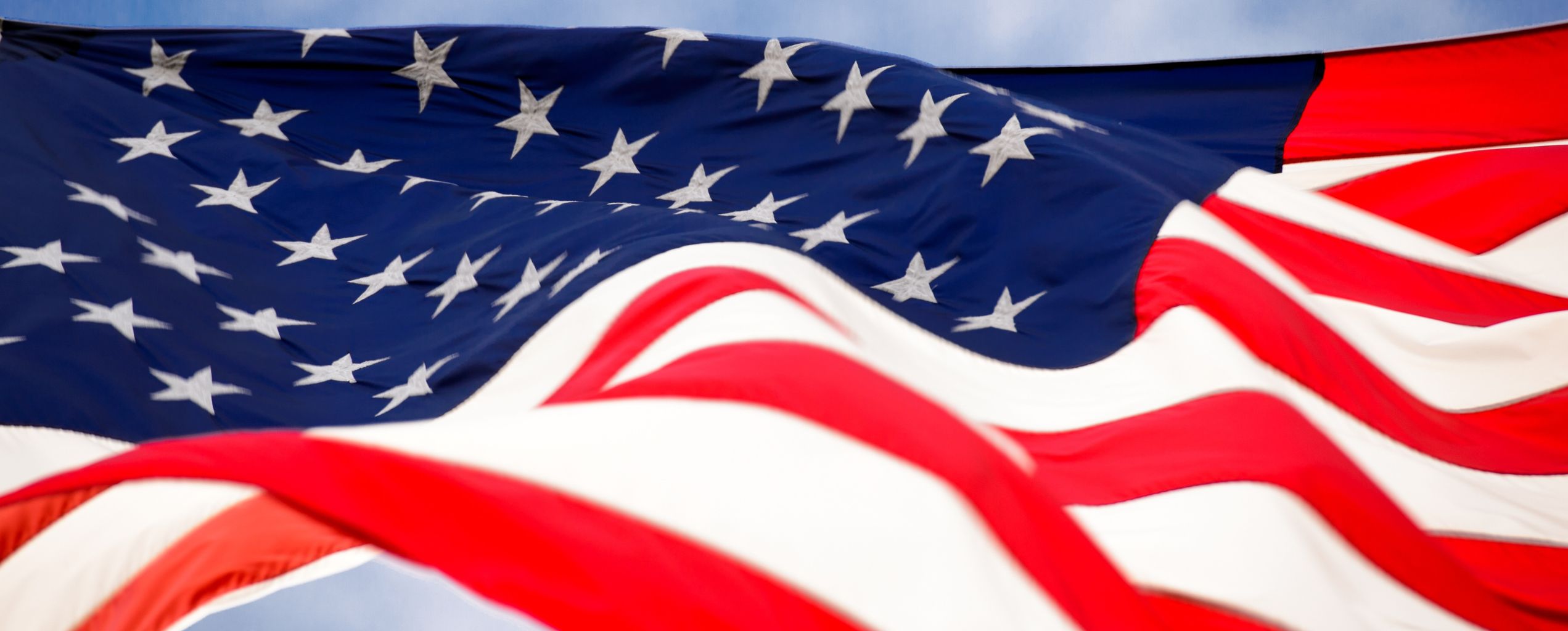 Close-up of the United States flag waving in the wind, showing stars on a blue background and red and white stripes.