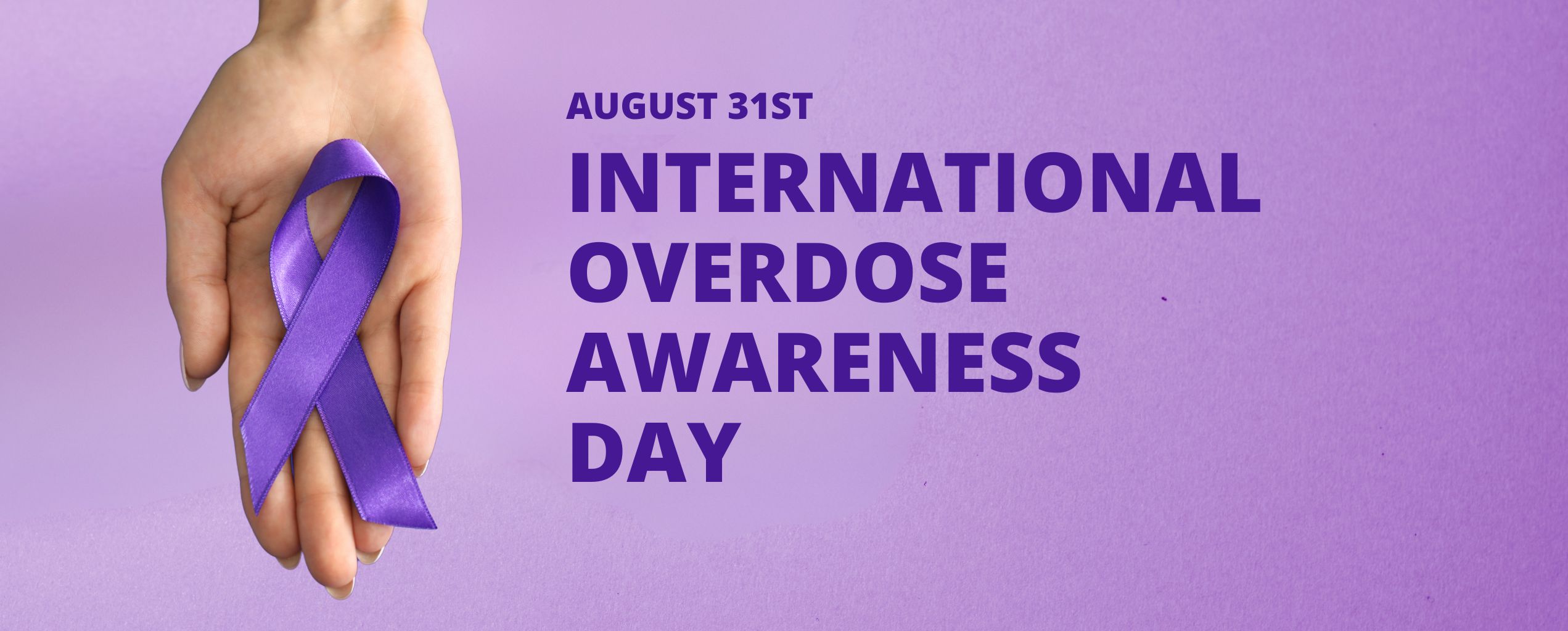 Hand holding a purple awareness ribbon on a purple background with the text 'August 31st International Overdose Awareness Day'.