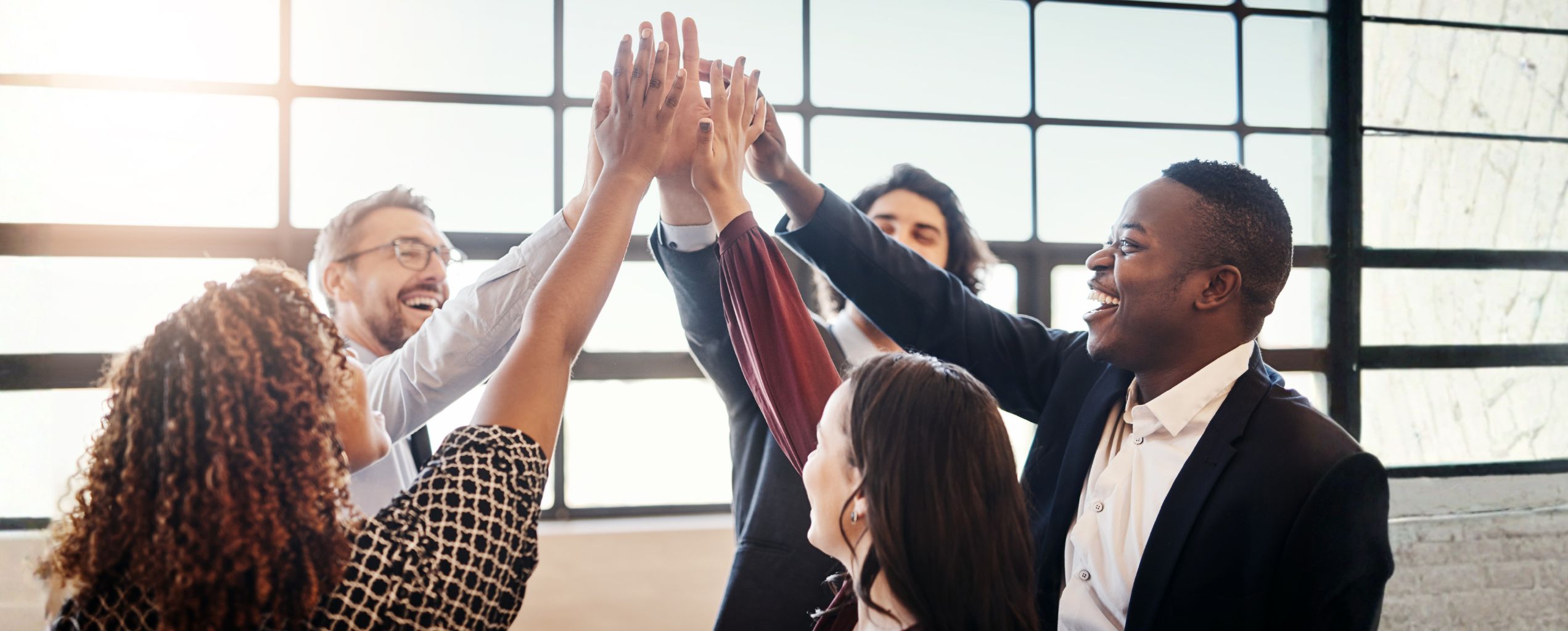 Five employees high-fiving at work. 