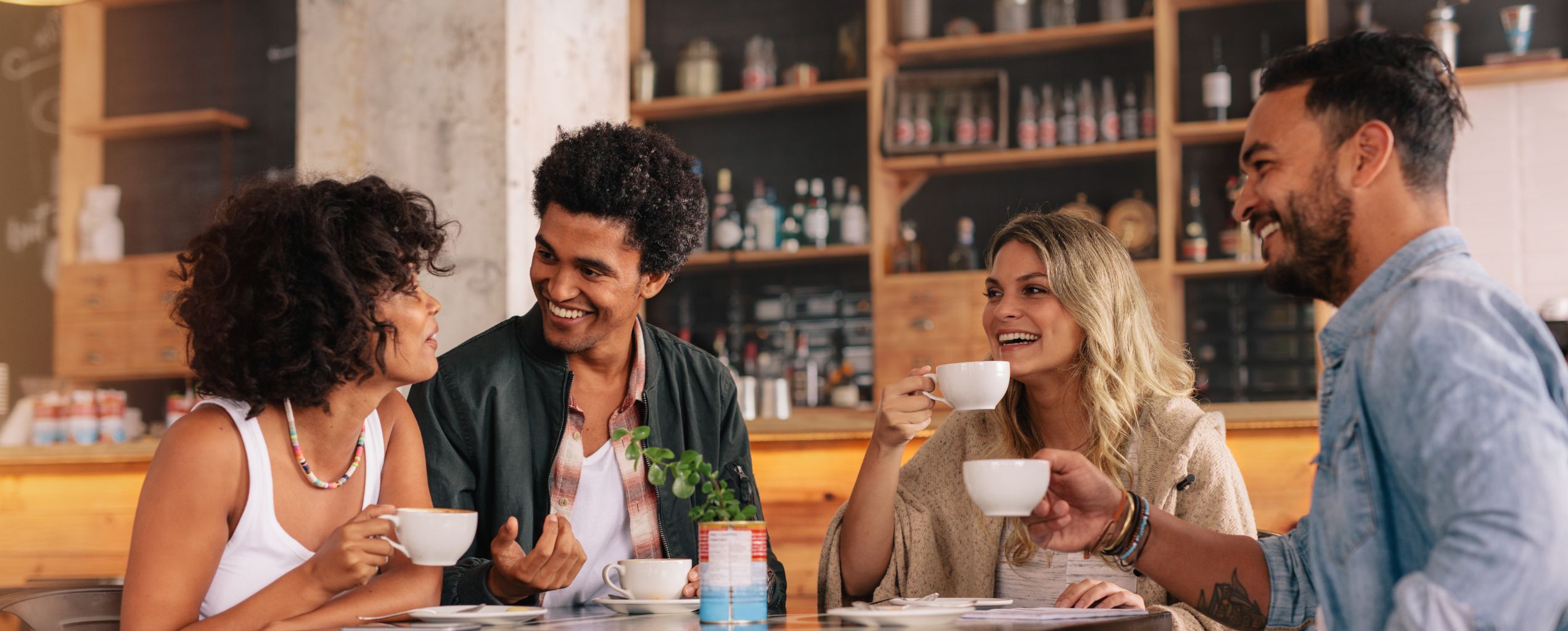 Four adults smiling and talking at a coffee shop.
