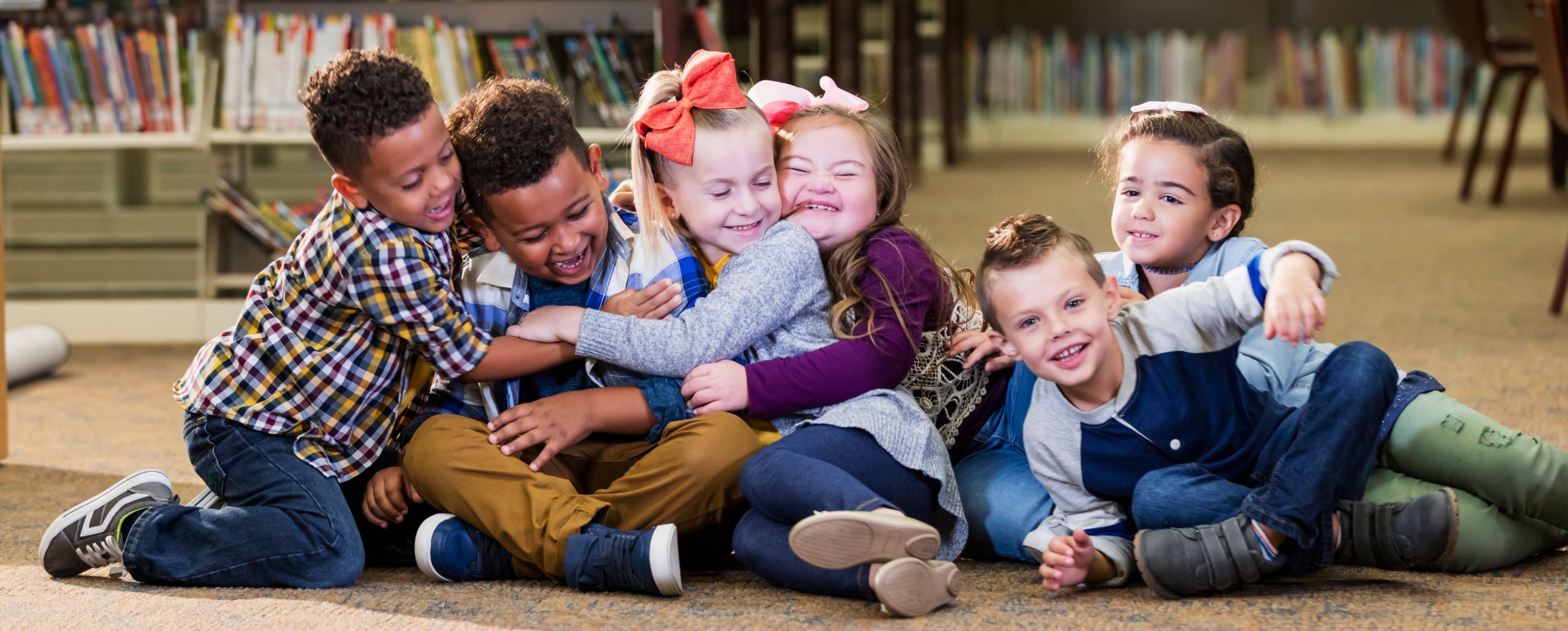 Six elementary-age children smiling and hugging each other
