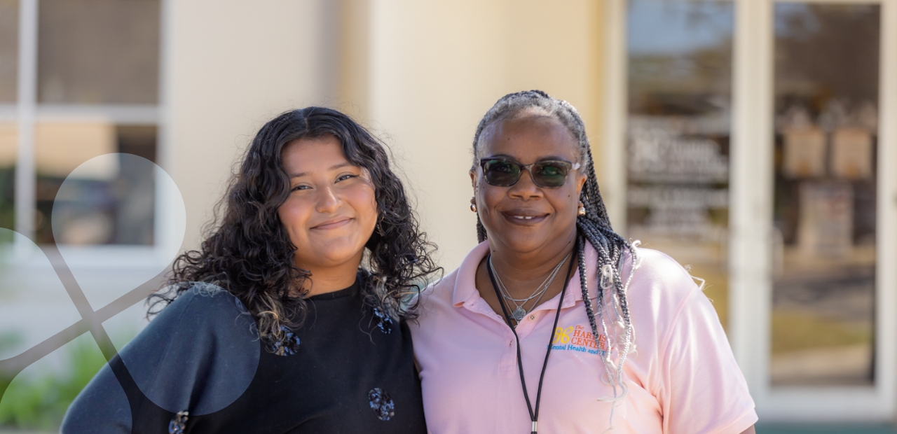 Two Harris County Mental Health staff members standing outside of a care facility, smiling for a portrait